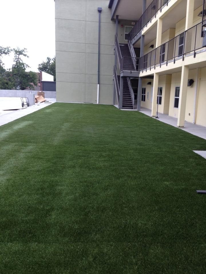 A green artificial turf lawn next to a building with stairs.