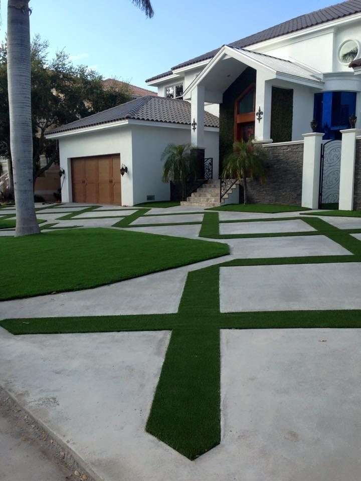 Modern driveway with concrete slabs and artificial grass strips.
