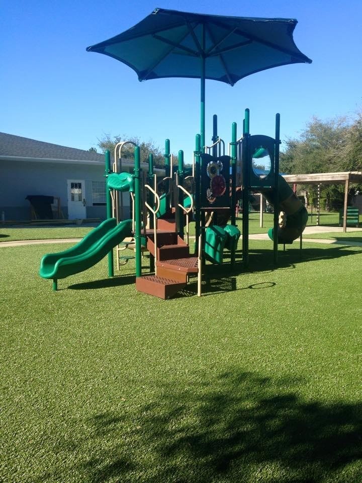 Children's playground with slides and climbing structures under a blue umbrella.