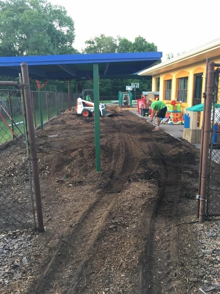Newly cleared and leveled backyard area with a blue canopy and garden tools.