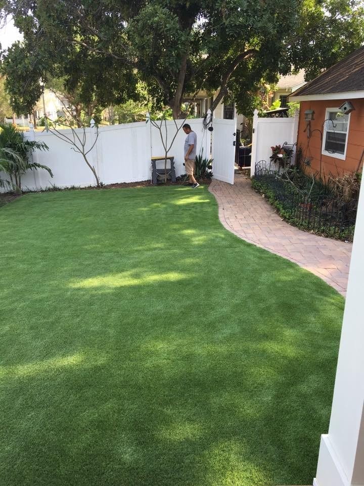 A well-maintained backyard with lush green grass and a curved stone pathway.