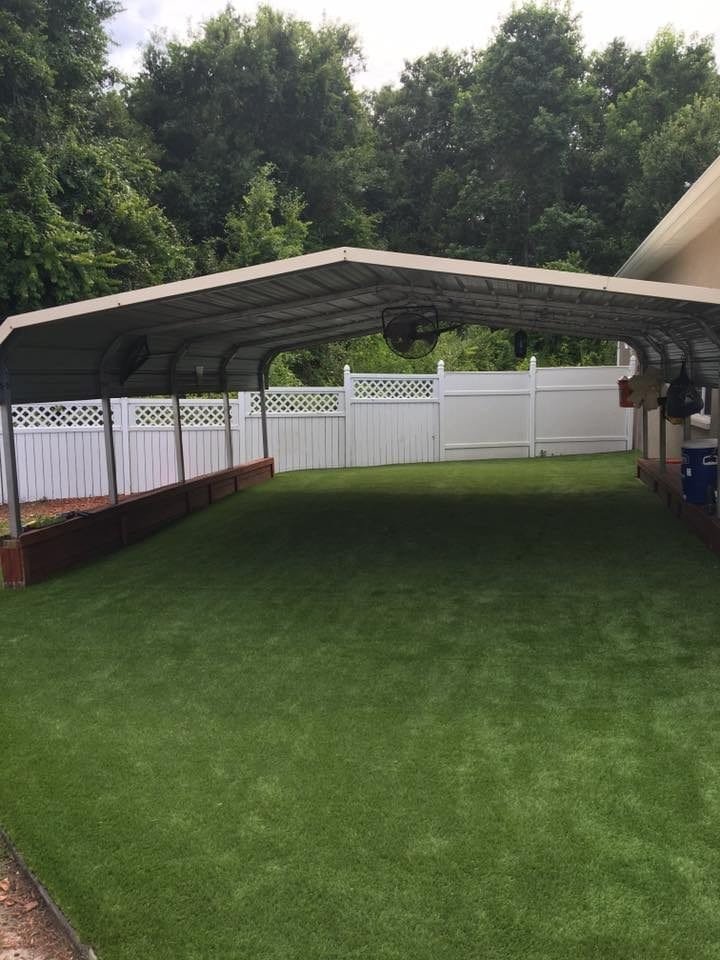 Covered outdoor area with artificial grass and white fence.