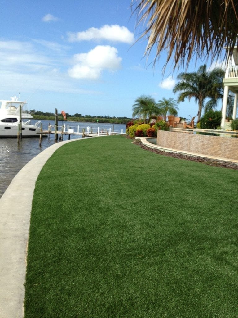 A manicured grassy area beside a marina with boats docked.