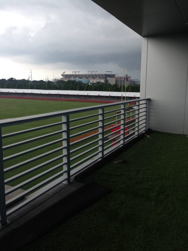 View from a balcony overlooking a sports field under a cloudy sky.