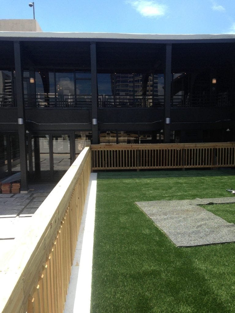 Modern outdoor space with green grass and wooden railing at dusk.