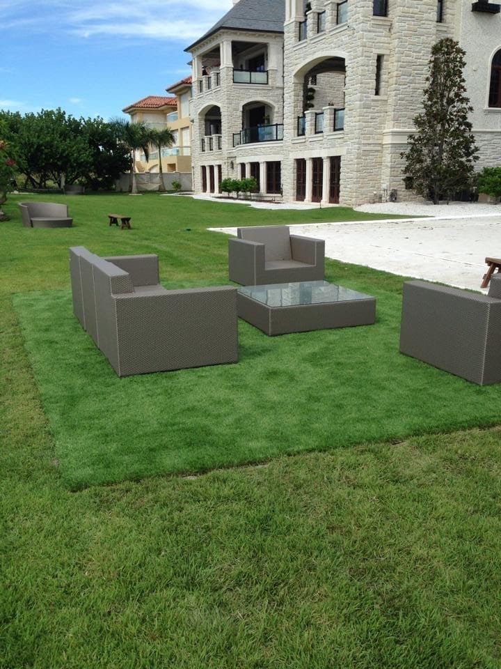 Modern outdoor patio furniture set on a green lawn near a building.