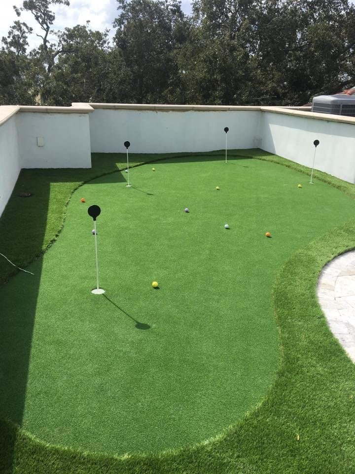 A backyard putting green with golf balls and flags.