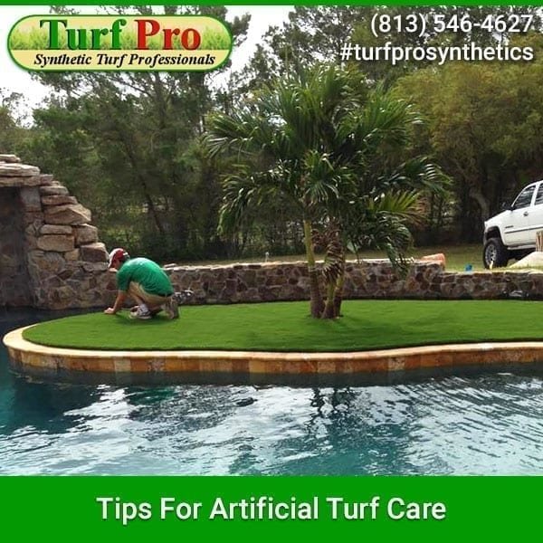 Gardener tending to artificial turf with palm trees in the background.