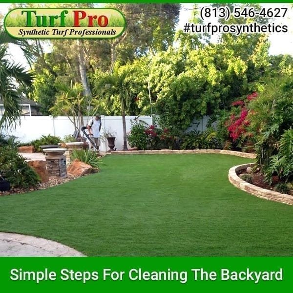 A clean backyard with well-maintained artificial turf and lush greenery.