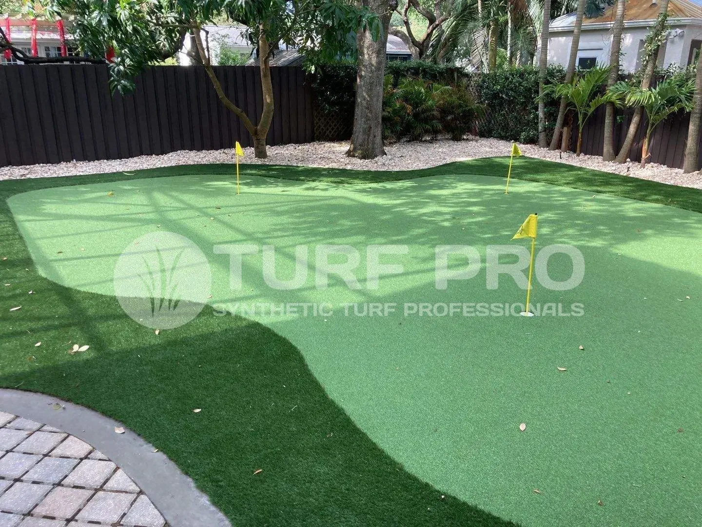 Artificial turf installed in a backyard with trees and a fence.