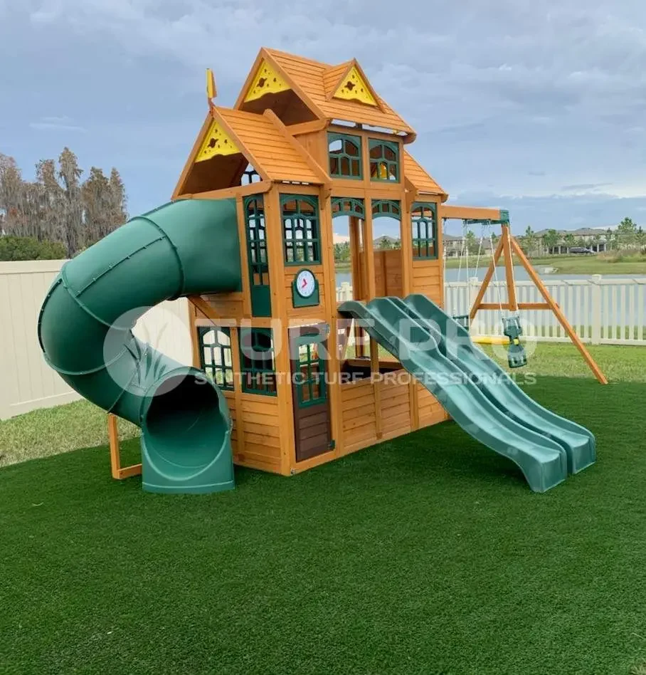 Large wooden playground with slides and swings on artificial grass.