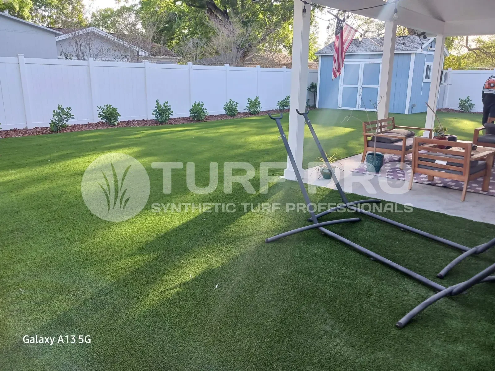 A well-maintained artificial turf lawn with a patio table and chairs in a backyard.