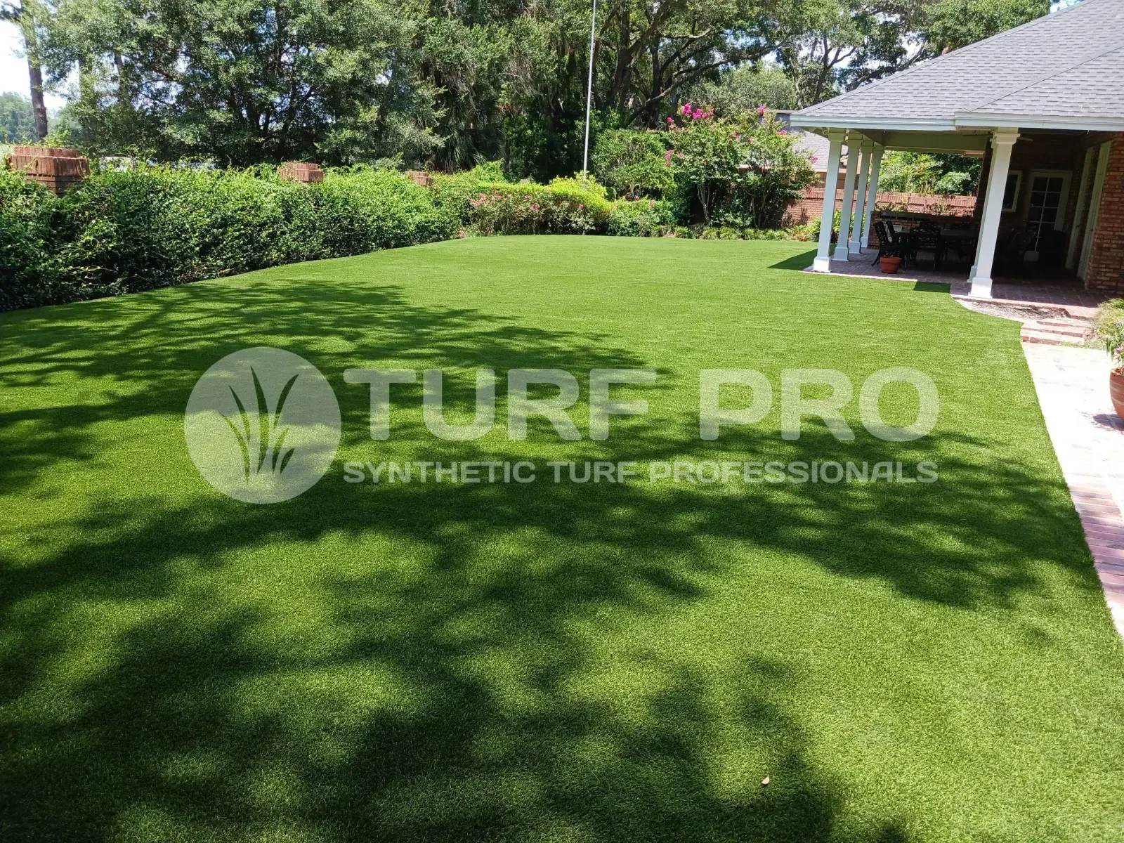 A freshly installed, lush green synthetic turf lawn in a sunny backyard.