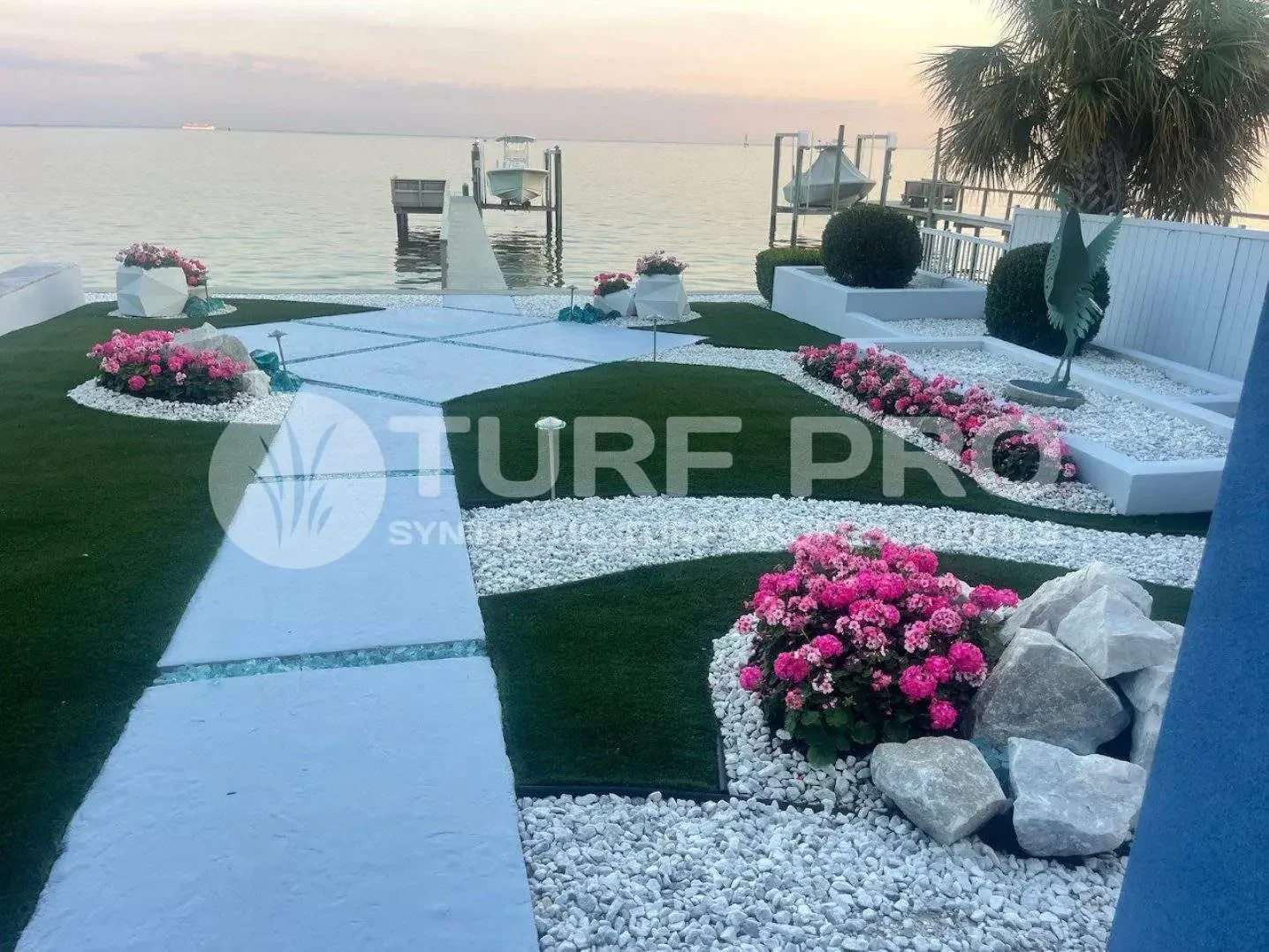Elegant outdoor space with pool, flowers, and sea view at sunset.