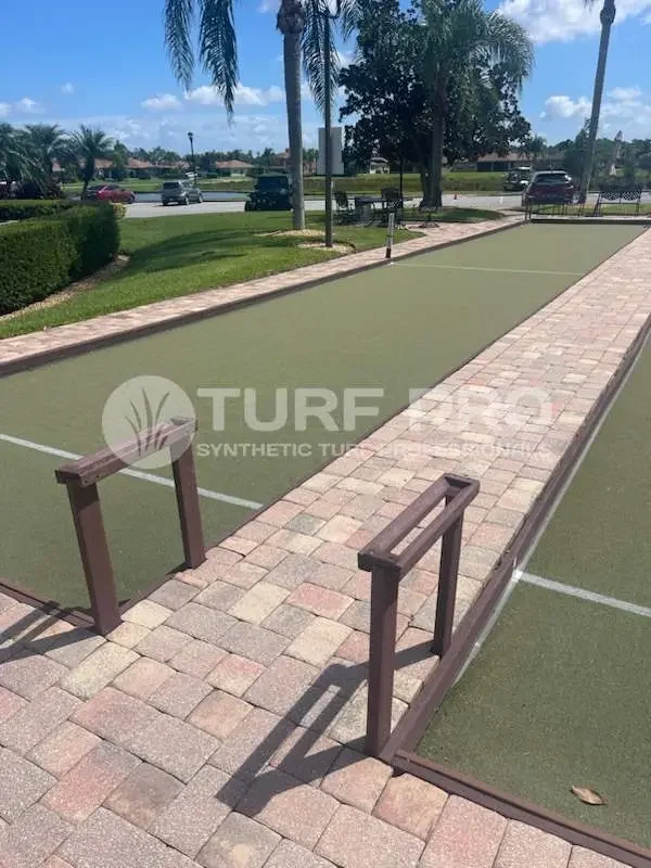 A bocce ball court with a brick walkway and wooden railings.