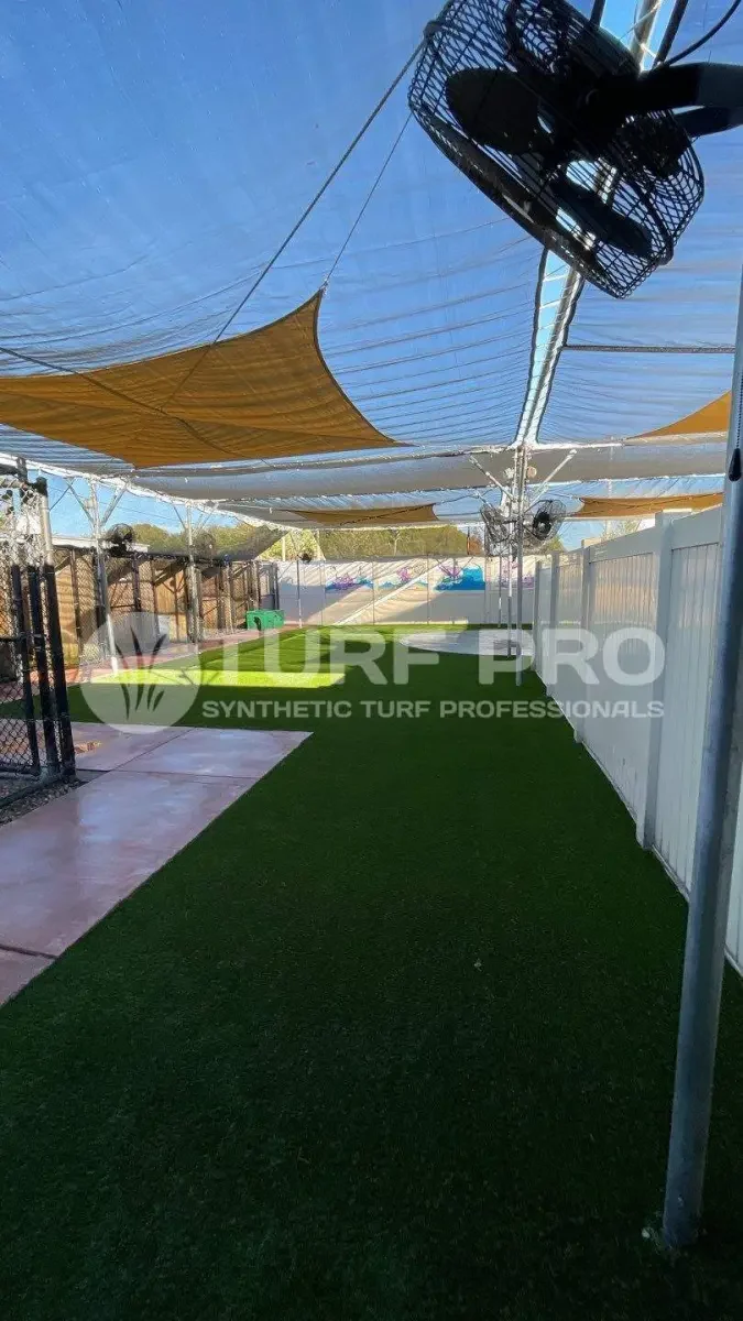 Backyard with synthetic turf under a yellow shade canopy.