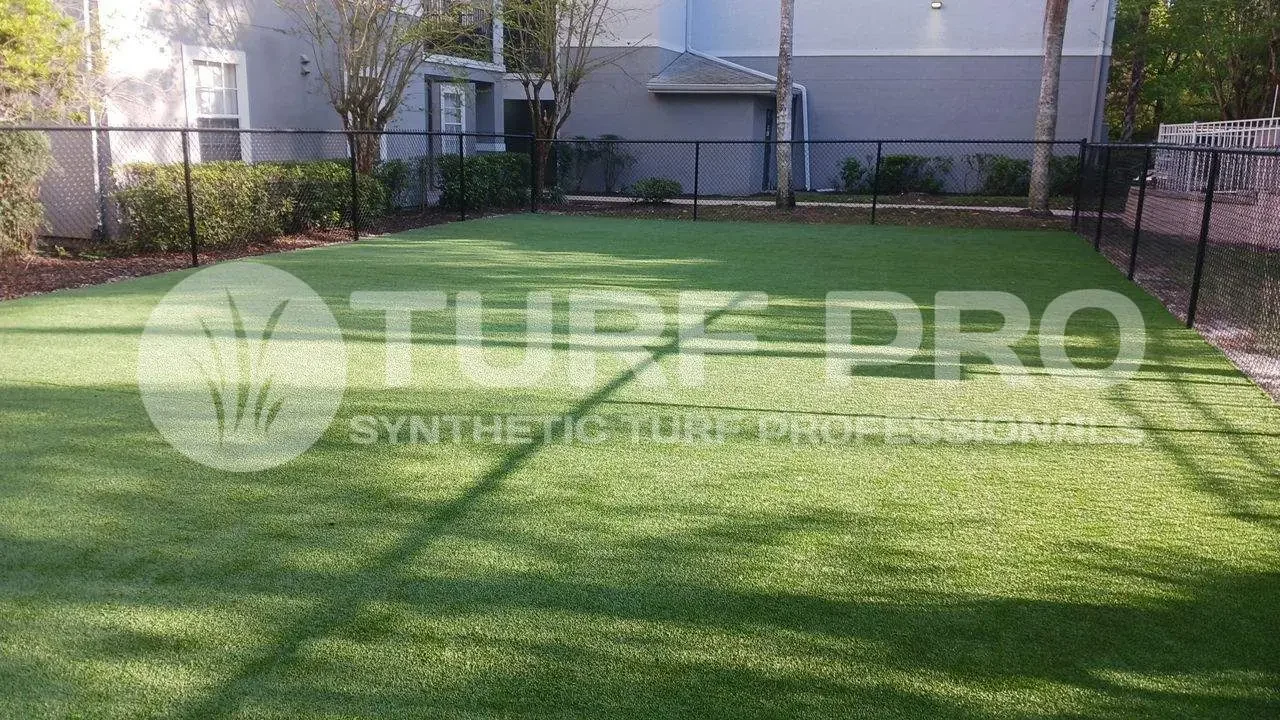 Empty synthetic turf sports field with goalposts and building in background.