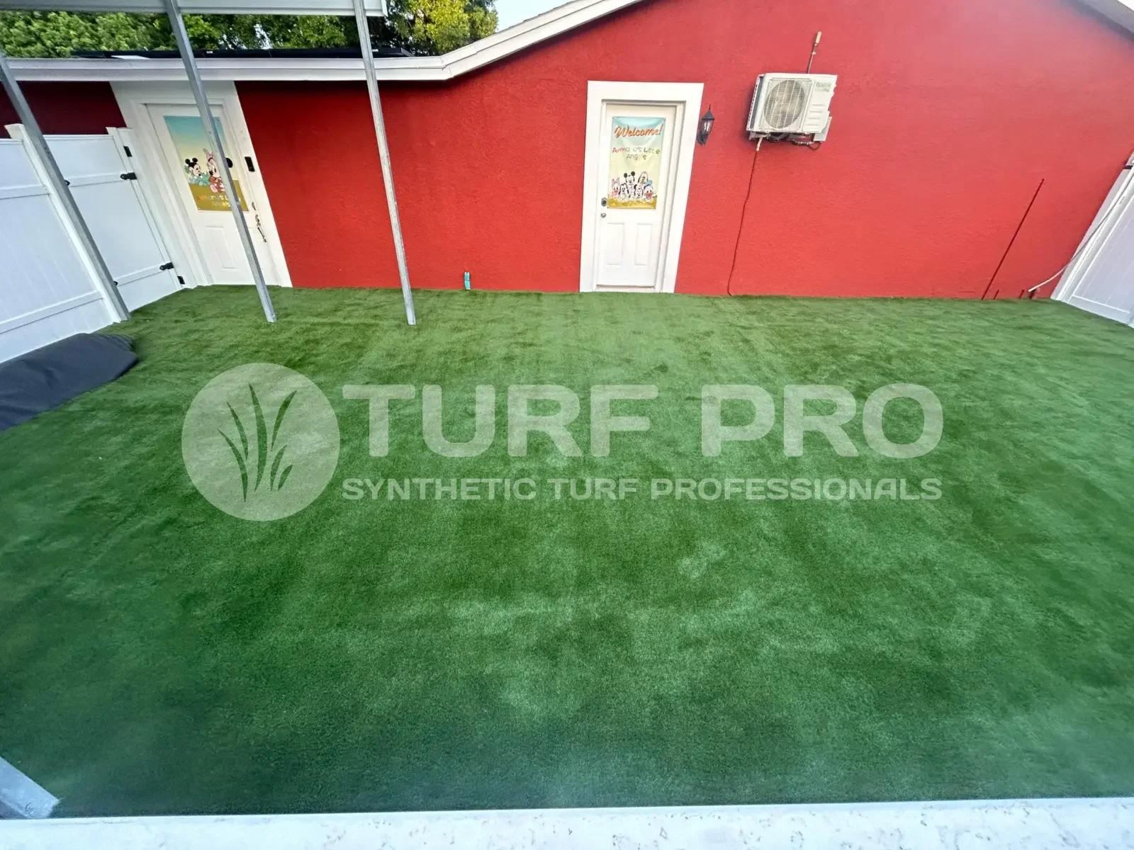 Artificial turf installed in a small outdoor area with red walls.