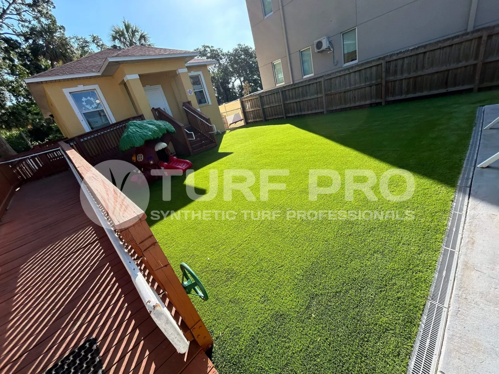 A backyard featuring freshly installed artificial turf with a wooden fence.