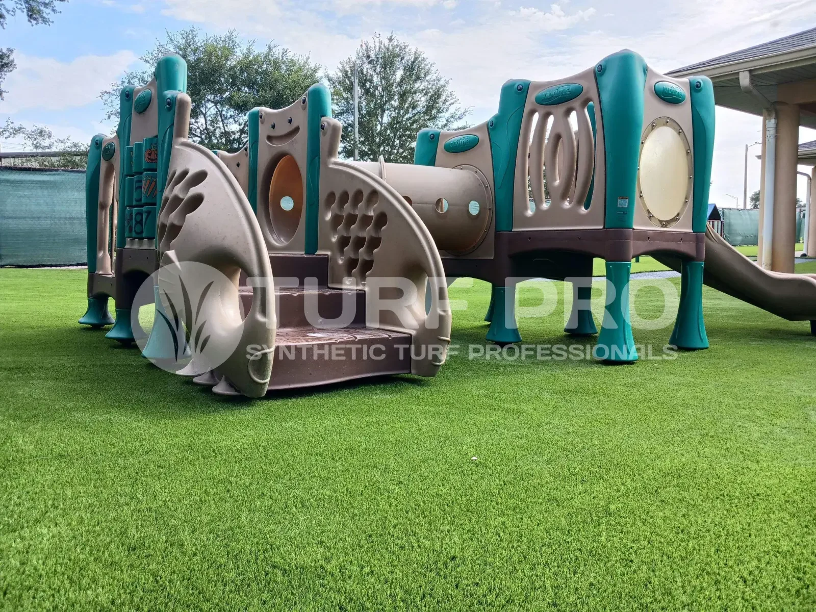 A colorful playground tunnel structure on artificial grass.