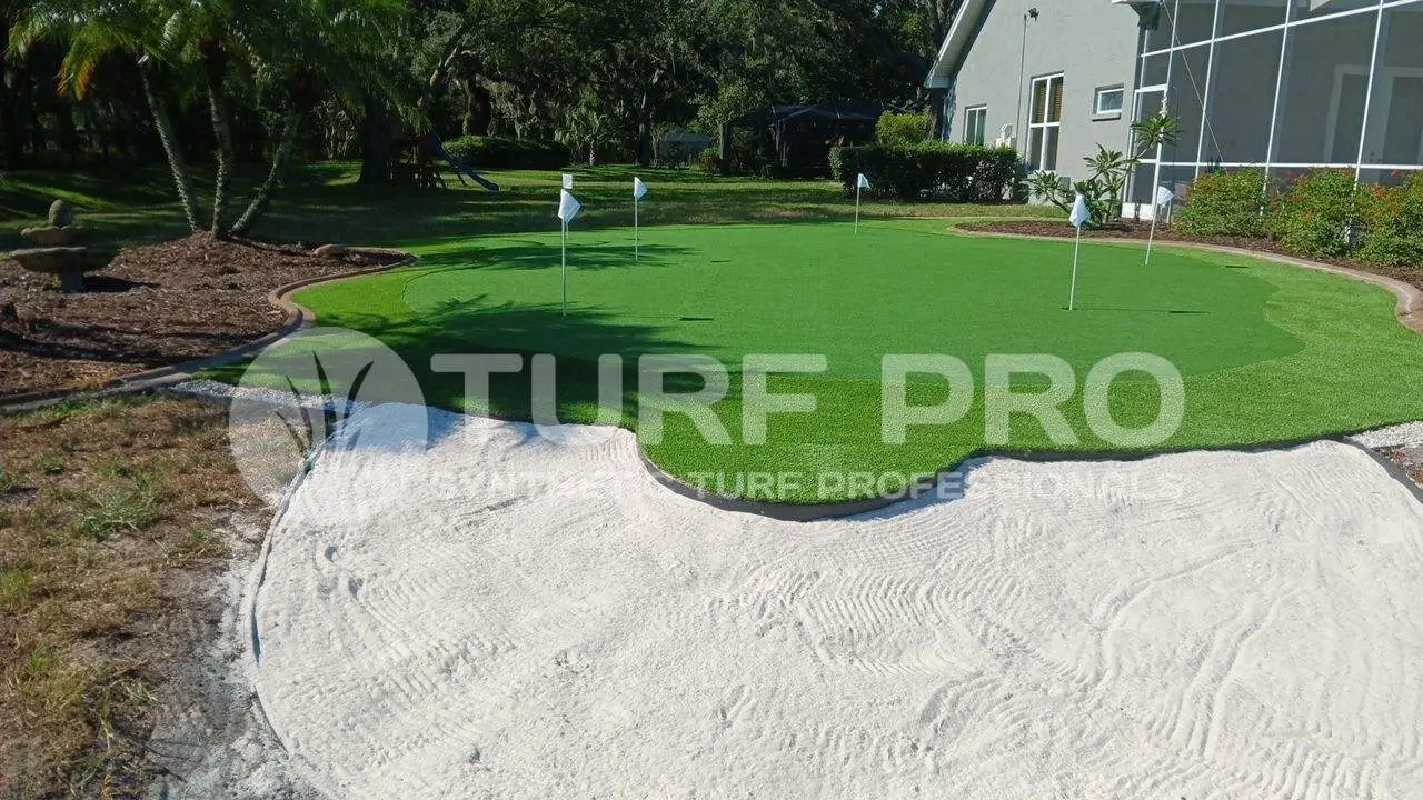 Golf course bunker with sand and putting green in the background.